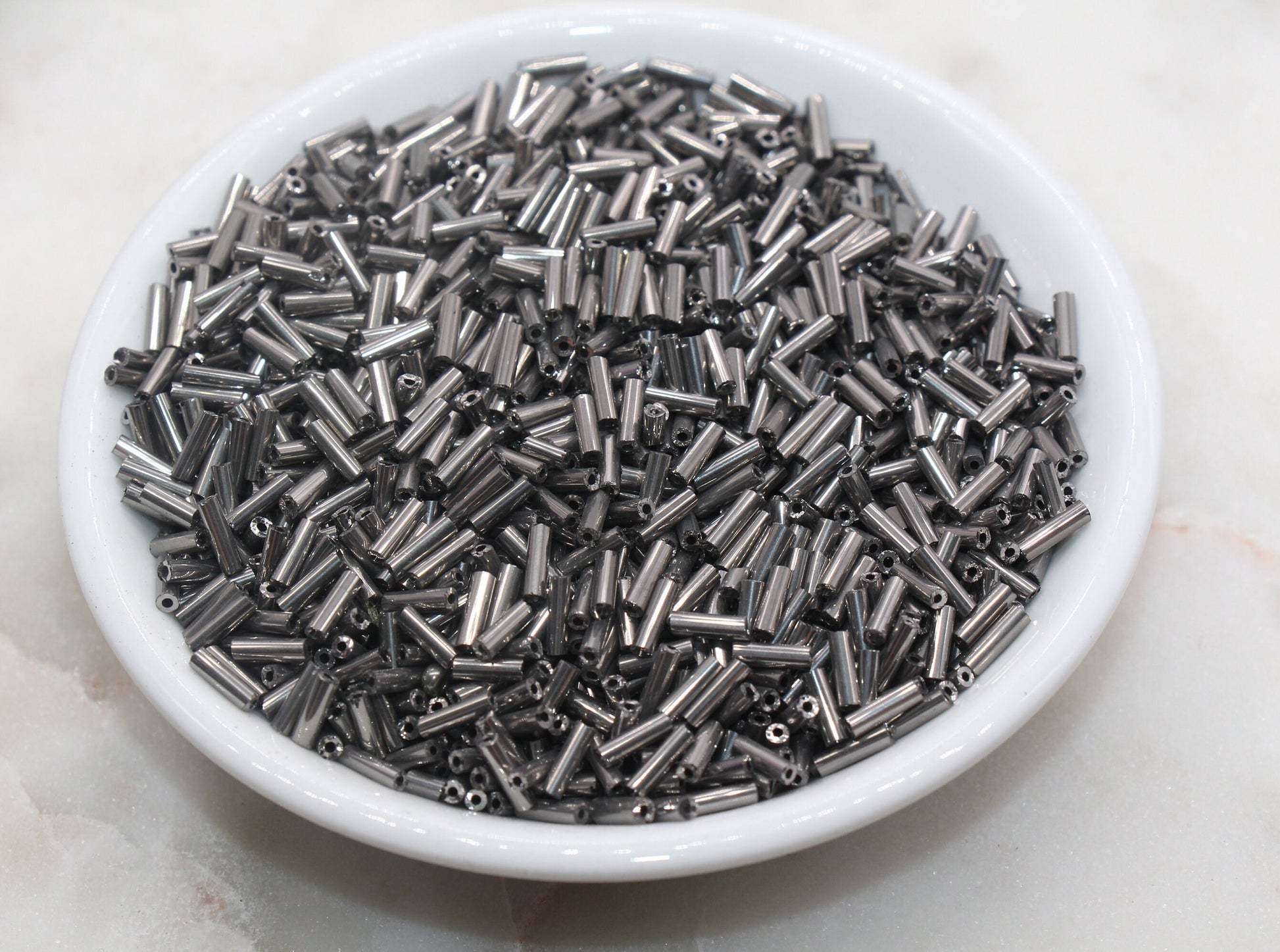 6mm Gunmetal Bugle Beads, perfect for embellishing clothing, accessories, and craft projects.